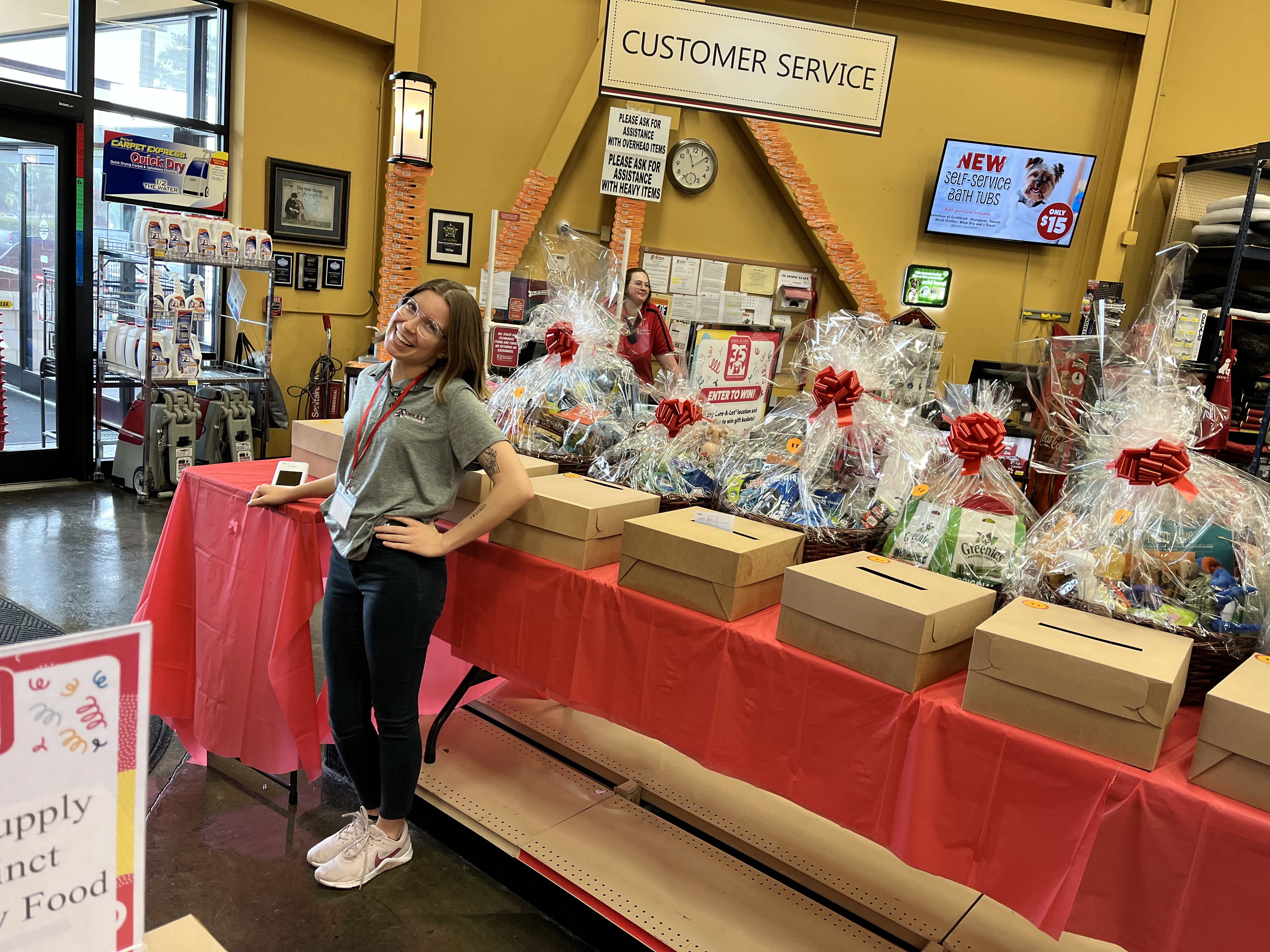 Care-A-Lot Staff standing infront of an array of raffle baskets filled with pet supplies